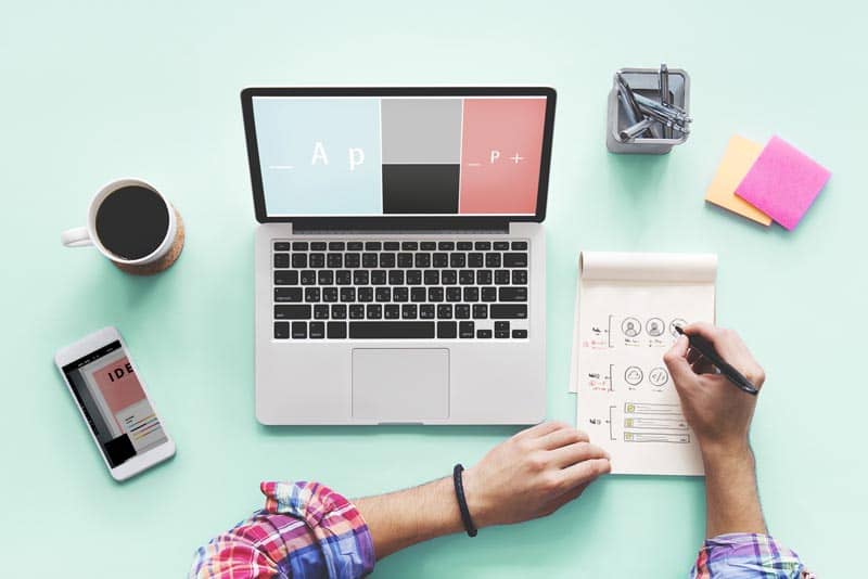 Website services popup, man at desk with laptop, phone, coffee, and notebook